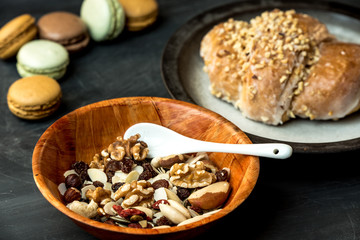 pie with apples and nuts surrounded by nuts and macaroons on a dark, rustic table
