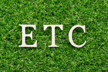Wood alphabet in word etc (abbreviation of et cetera)on artificial green grass background