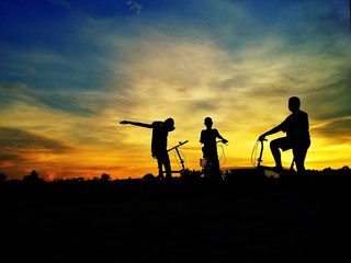 Fototapeta na wymiar Silhouette of boys with bike in beautiful light.