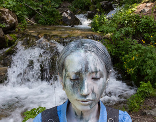 Girl Office worker, outdoors with a makeup on her face imitating a mountain stream. The girl merges...