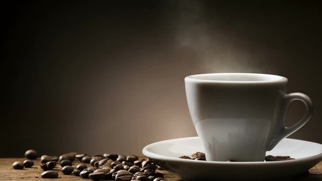 Animated looping image, steamed hot cup of coffee with coffee beans on wooden table.
