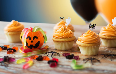 food, baking and holidays concept - cupcakes or muffins and candies with halloween party...