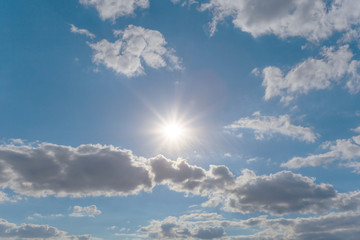 Fototapeta na wymiar sparkle sun on the blue cloudy sky, nature background