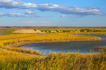 small lake among a prairies under a blue cloudy sky