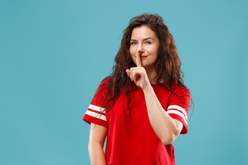 Secret, gossip concept. Young woman whispering a secret behind her hand. Business woman isolated on trendy blue studio background. Young emotional woman. Human emotions, facial expression concept.