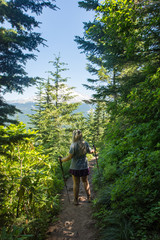 A blonde female hiker makes her way through the forest on the Mirror Lake Trail in the Mount Hood National Forest in central Oregon