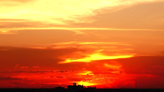  4K orange sunset as the massive sun sets into the horizon above the city