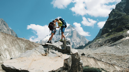 loving couple of tourists with backpacks in the hike kiss on the top in the mountains. The concept of love, achievement of the goal and success