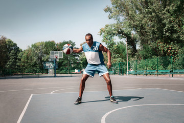 Obraz premium Picture of young confused african basketball player practicing outdoor. Fit afro man in motion and movement. athletic and sport lifestyle concept