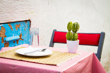 Pot with a cactus on a table with a checkered tablecloth on a narrow street in the medina of...