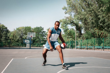 Obraz premium Picture of young confused african basketball player practicing outdoor. Fit afro man in motion and movement. athletic and sport lifestyle concept