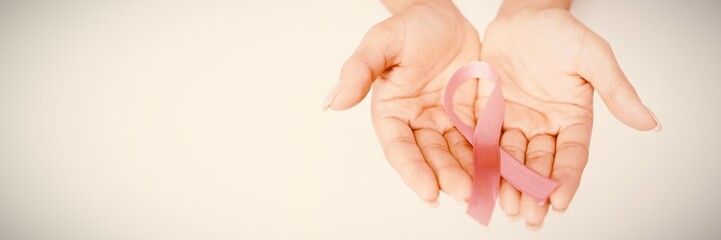 Two hands displaying pink ribbon for breast cancer awareness