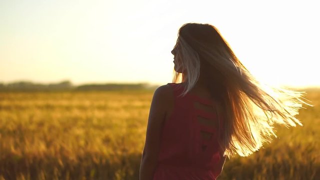 Young beautiful girl in red dress in the field at sunset. Slow motion. HD