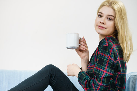 Teenage woman sitting on sofa with mug