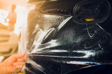 Naklejka na ściany i meble Worker hands installs car paint protection film wrap.