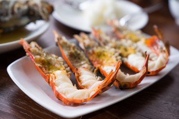 Close up Grilled prawns or fresh grilled shrimps ,cooking seafood with salad on white dish in Thai restaurant. Selective focus