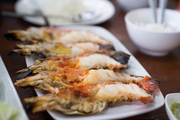 Close up Grilled prawns or fresh grilled shrimps ,cooking seafood with salad on white dish in Thai restaurant. Selective focus