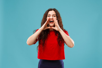 Do not miss. Young casual woman shouting. Shout. Crying emotional woman screaming on studio background. Female half-length portrait. Human emotions, facial expression concept. Trendy colors