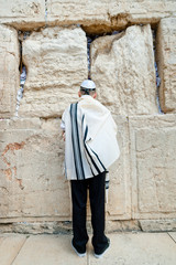 young jew boy praying near western wall in talit after his barmitzvah