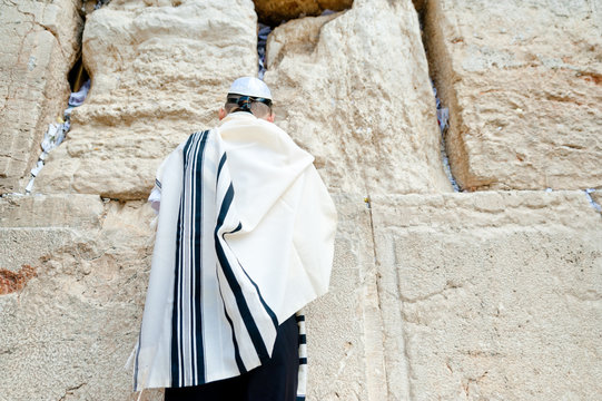 young jew boy praying near western wall in talit after his barmitzvah