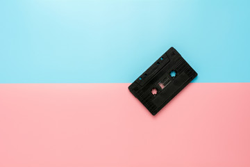 Fototapeta premium black tape cassette on blue and pink background.