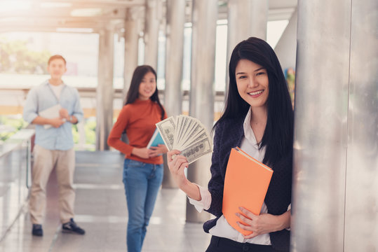 Asian Girl Happy Holding Money In Hand With A Group Of Friends In The City.Education And Business Concept