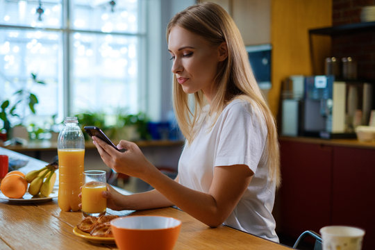 Woman eats breakfast and uses her mobile phone