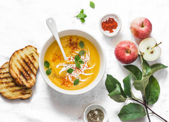 Roasted pumpkin and apples vegetarian soup on light background, top view. Flat lay. Healthy vegetarian food concept