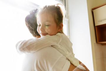 Family. Love. Parenthood. Dad and his little daughter are hugging, girl is smiling. In the kitchen...