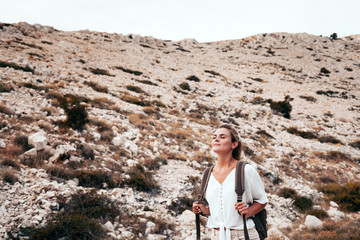 Beautiful tourist girl on hiking trail in mountain looking at landscape