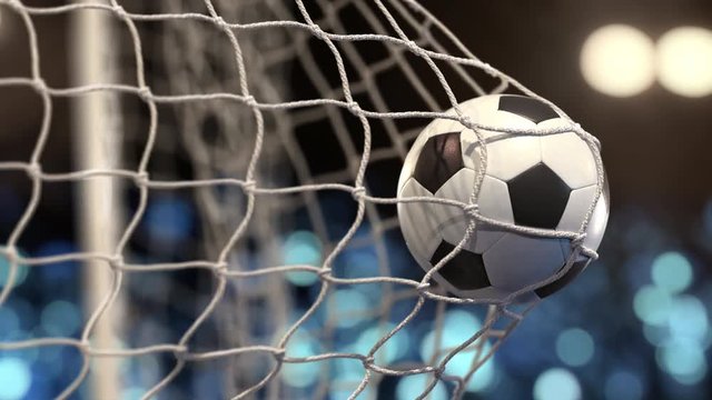 Soccer ball flies into the net on a stadium with yellow and blue lights. In slow motion