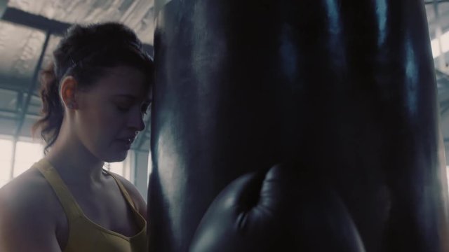 healthy woman athlete training kickboxing exercise workout punching bag strong female fighter exhausted resting after practice in fitness gym wearing boxing gloves