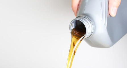 automotive oil in a hand a gray bottle on a light background