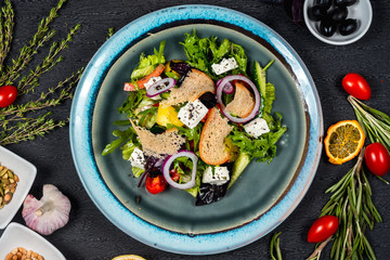 Fresh vegetable salad with cheese and slice of bread on blue plate
