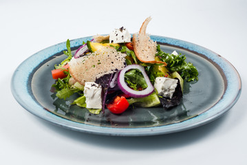 Fresh vegetable salad with cheese and slice of bread on blue plate
