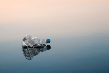 Concept of pollution, creative background. A plastic bottle floating in the ocean, non-decomposable...