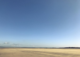 Fototapeta na wymiar Calm English seaside. Flat sand and blue sky