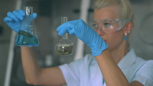 Female Researcher Examining a Test Tube In a Laboratory. HD