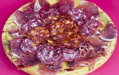 Typical spanish food with ham and sausage on a wooden plate