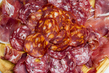Typical spanish food with ham and sausage on a wooden plate
