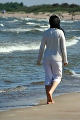 Fototapeta na wymiar Girl walks by the sea.