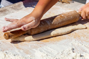 Woman's hands rolling out a dough with rolling pin