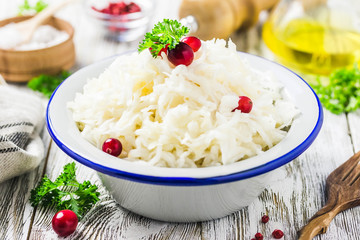Sauerkraut with parsley, cranberries in a bowl on wooden rustic background. Selective focus, space for text.