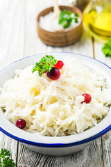 Sauerkraut with parsley, cranberries in a bowl on wooden rustic background. Selective focus, space for text.