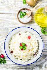 Sauerkraut with parsley, cranberries in a bowl on wooden rustic background. Top view, space for text.