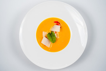 Pumpkin cream soup with slices of tender cheese