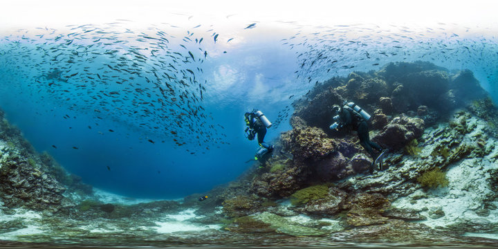 Undewater photo of scuba divers in the Galapagos islands with a school of fish 
