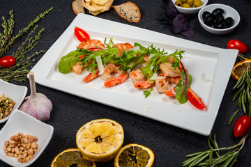 salad of fried shrimp with herbs and tomatoes on a white plate