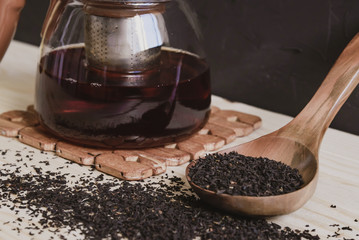 wooden spoon with black tea on the background
