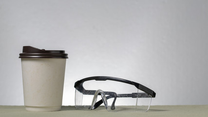 Safety glasses and white blank label coffee cup  on white background